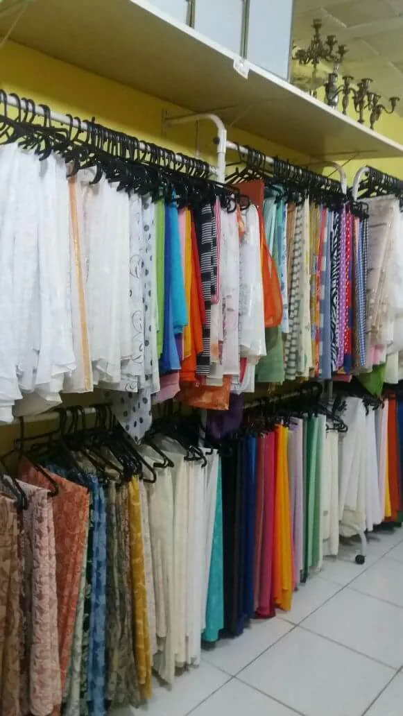 Vista da loja com araras de rendas, bordados e tecidos estampados